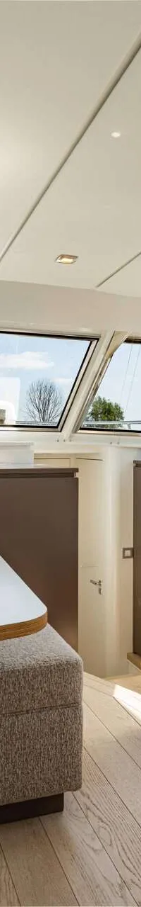 De foto toont een interieur van een boot met een zithoek, twee tafels, een keukenblok en grote ramen. — Vripack 63 Custom M/Y