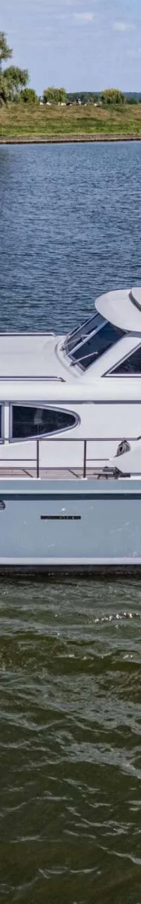 Een grijze motorboot vaart op een waterweg met een groene oever en bomen op de achtergrond. — Vripack 63 Custom M/Y