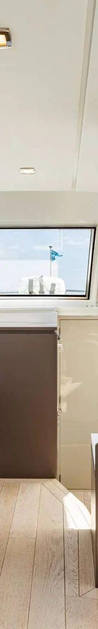 De foto toont het interieur van een boot met een zithoek, tafel, keukenblok en grote ramen. — Vripack 63 Custom M/Y