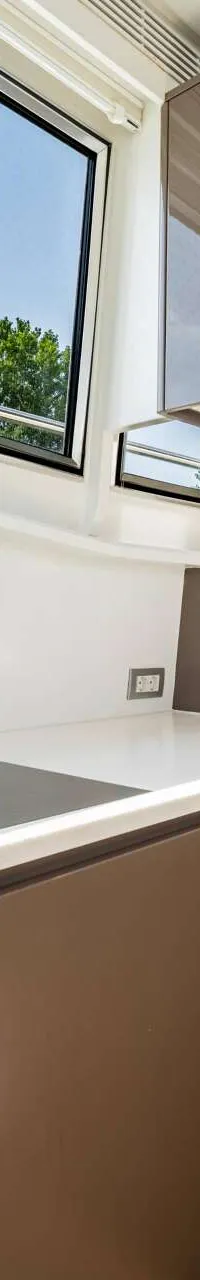 Een moderne kombuis met een witte aanrecht, inductiekookplaat, gootsteen, kranen en bruine kasten.