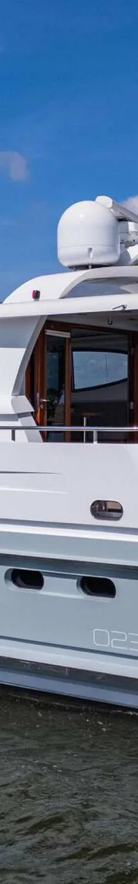 Een witte en lichtgrijze motorboot met de naam "IKIGAI" en "ZAANDAM" op de spiegel, vaart op een waterweg.