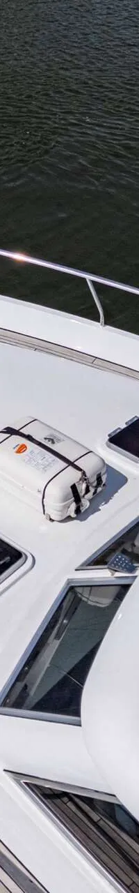 Een bovenaanzicht van de boeg van een witte motorboot met een teakhouten dek en een reddingsvlot. — Vripack 63 Custom M/Y