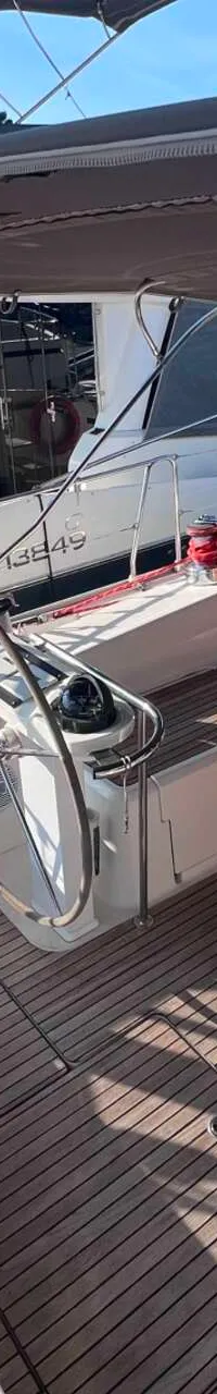 De foto toont het teakdek van een zeilboot met twee stuurwielen, een inklapbare tafel en een grijze bimini.