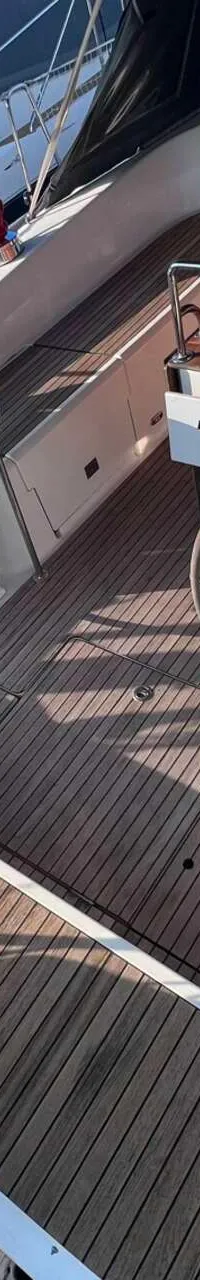 De foto toont het dek van een zeilboot met twee stuurwielen, een houten tafel en een teakhouten vloer. — Bavaria 55 Cruiser