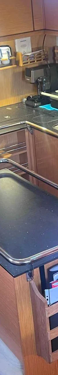 Een kombuis met een aanrecht, spoelbak, kookplaat, oven, magnetron en diverse opbergkasten.