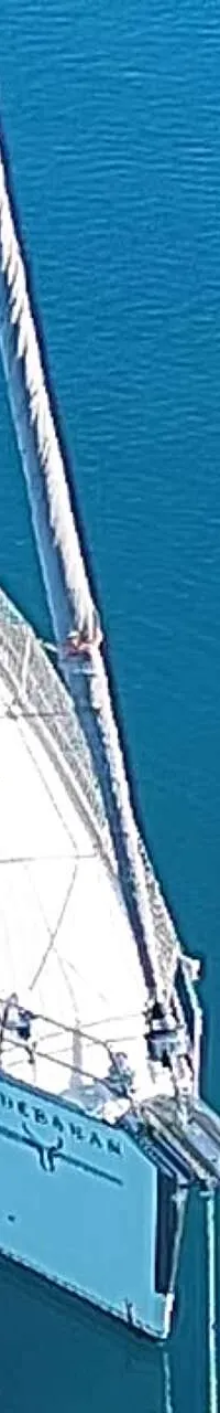 Een witte zeilboot met de naam "ALDEBARAN" ligt in helder blauw water, gezien vanaf de voorkant. — Bavaria 55 Cruiser