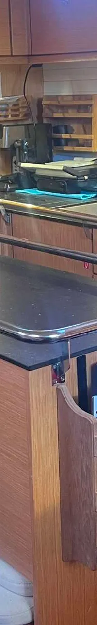 Een houten scheepskeuken met een fornuis, oven, gootsteen, magnetron en een verrijdbaar eiland met opbergruimte.