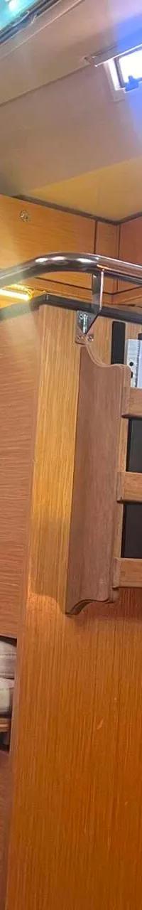 De foto toont een interieur van een boot met houten kasten, een oven, een magnetron en een open deur. — Bavaria 55 Cruiser