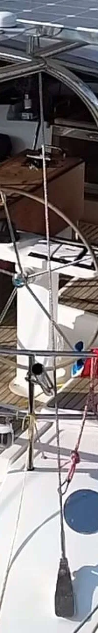 Een bovenaanzicht van een zeilboot met een houten dek, stuurwiel, zonnepanelen en de naam "ALDEBARAN" op de achtersteven.