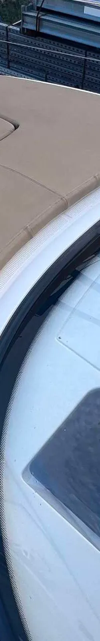 Een detailfoto van de boeg van een boot met een beige zonnedek en een voorruit. — Bavaria S29