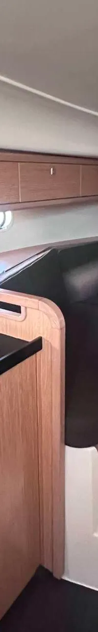 Een interieur van een boot met een keukenblok, een zithoek met tafel en opbergkasten. — Bavaria S29