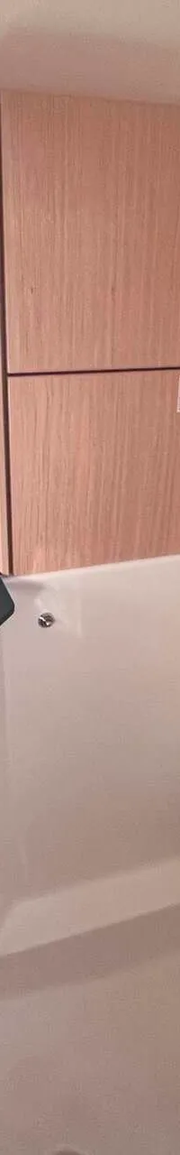 De foto toont een badkamer met een toilet, een wastafel met kraan, een spiegel en houten kasten.