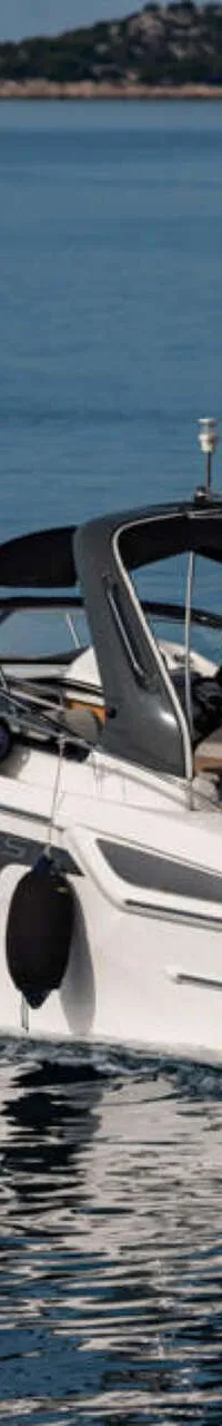 Een witte motorboot met een zwarte streep vaart over blauw water, met een persoon aan het roer en een vlag op het dak.