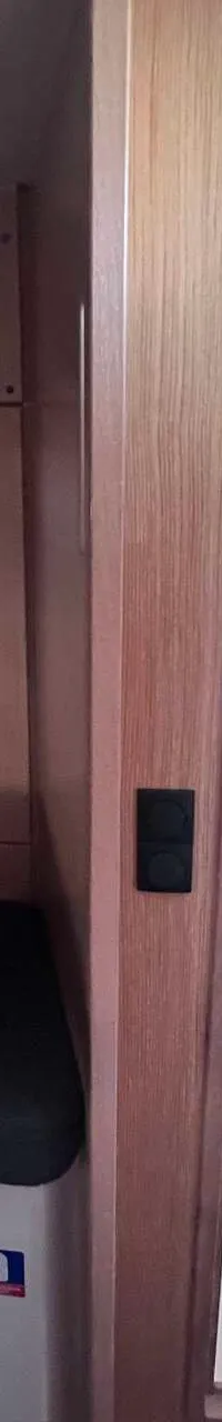 Een interieur van een boot met een tafel, banken, een televisie, bedieningspanelen en een open deur naar een badkamer.