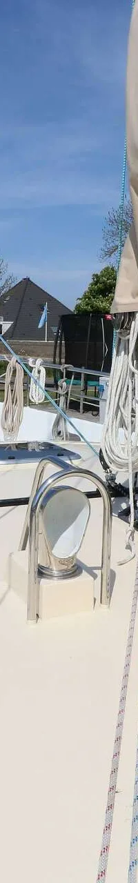 Een bovenaanzicht van het dek van een zeilboot met een opgerold zeil, touwen, lieren en een reling. — Noordkaper 48 -S