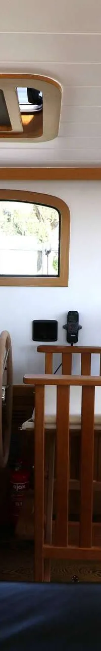 De foto toont het interieur van een boot met een stuurstand, houten meubilair, ramen en een tafel. — Noordkaper 48 -S