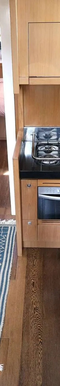 Een interieur van een boot met een kombuis, eethoek en een doorgang naar een slaapcabine. — Noordkaper 48 -S
