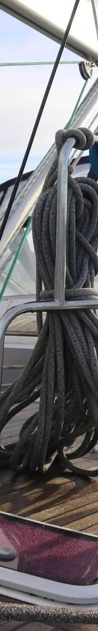 Een dek van een zeilboot met een reddingsvlot, mast, touwen, een luik en een witte ventilatiekap. — Beneteau 57
