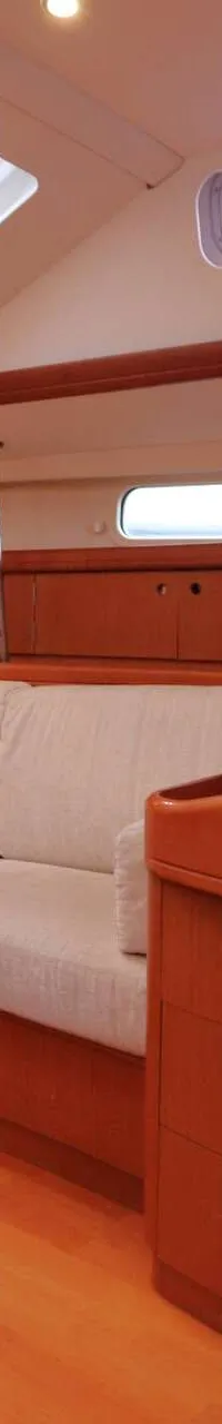 De foto toont een houten interieur van een boot met een bank, een bureau, navigatieapparatuur en een brandblusser.