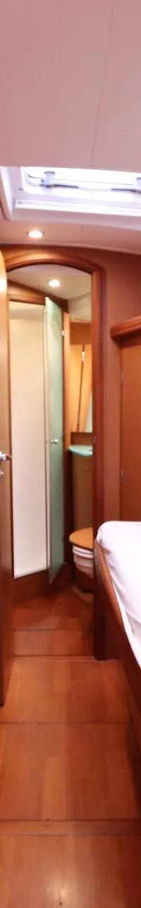 Een houten gang met een bed aan de rechterkant, een deur aan de linkerkant en een open deur aan het einde van de gang.