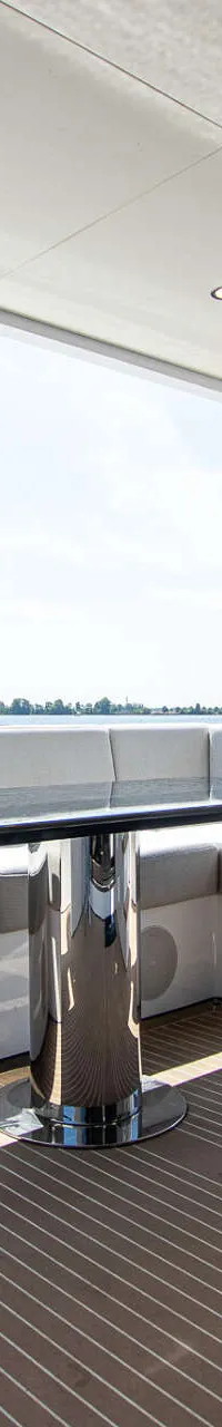 Een dek met een L-vormige bank, een tafel, een trap en een Nederlandse vlag op de achtergrond.