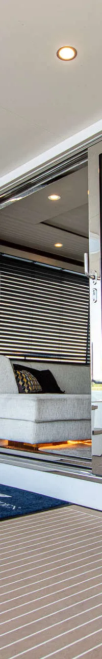 Een witte trap met houten treden en een zwart metalen leuning leidt naar een hoger dek, naast een glazen schuifdeur.