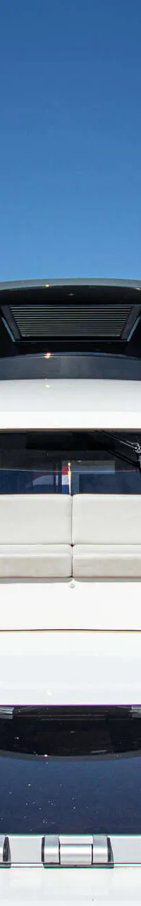 De foto toont het voordek van een wit motorjacht met een beige dek en een zithoek.