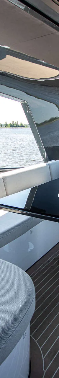 Een open kuip met een U-vormige bank, een glanzende zwarte tafel en een gestreepte vloer, met uitzicht op water en bomen.