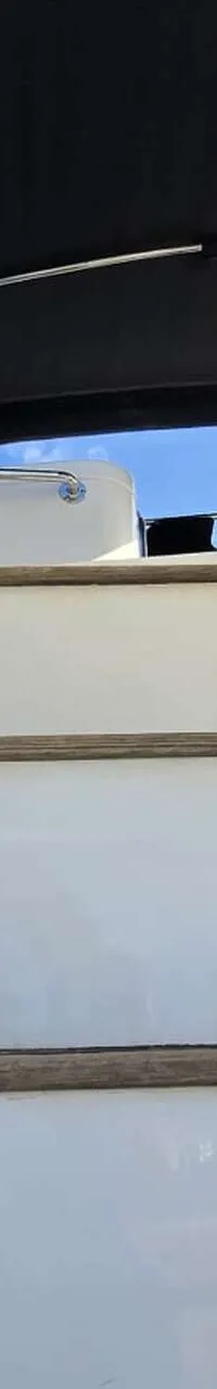 Een witte boot met houten treden en een metalen reling, met een "DE VALK YACHT BROKERS" logo en "JOHNSON S6" tekst.