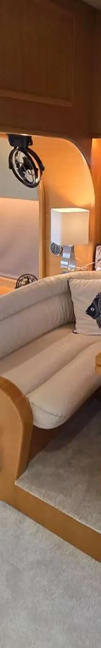 De foto toont het interieur van een boot met een zithoek, een tafel en een trap naar een hoger gelegen dek. — Johnson 56