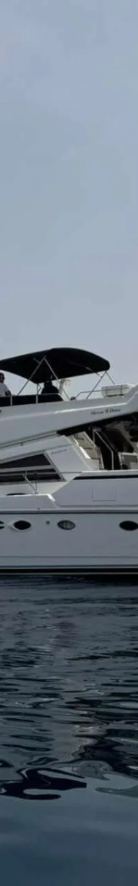 Een witte motorboot met de naam "Ocean Drive" vaart op kalm water onder een lichtgrijze lucht. — Johnson 56