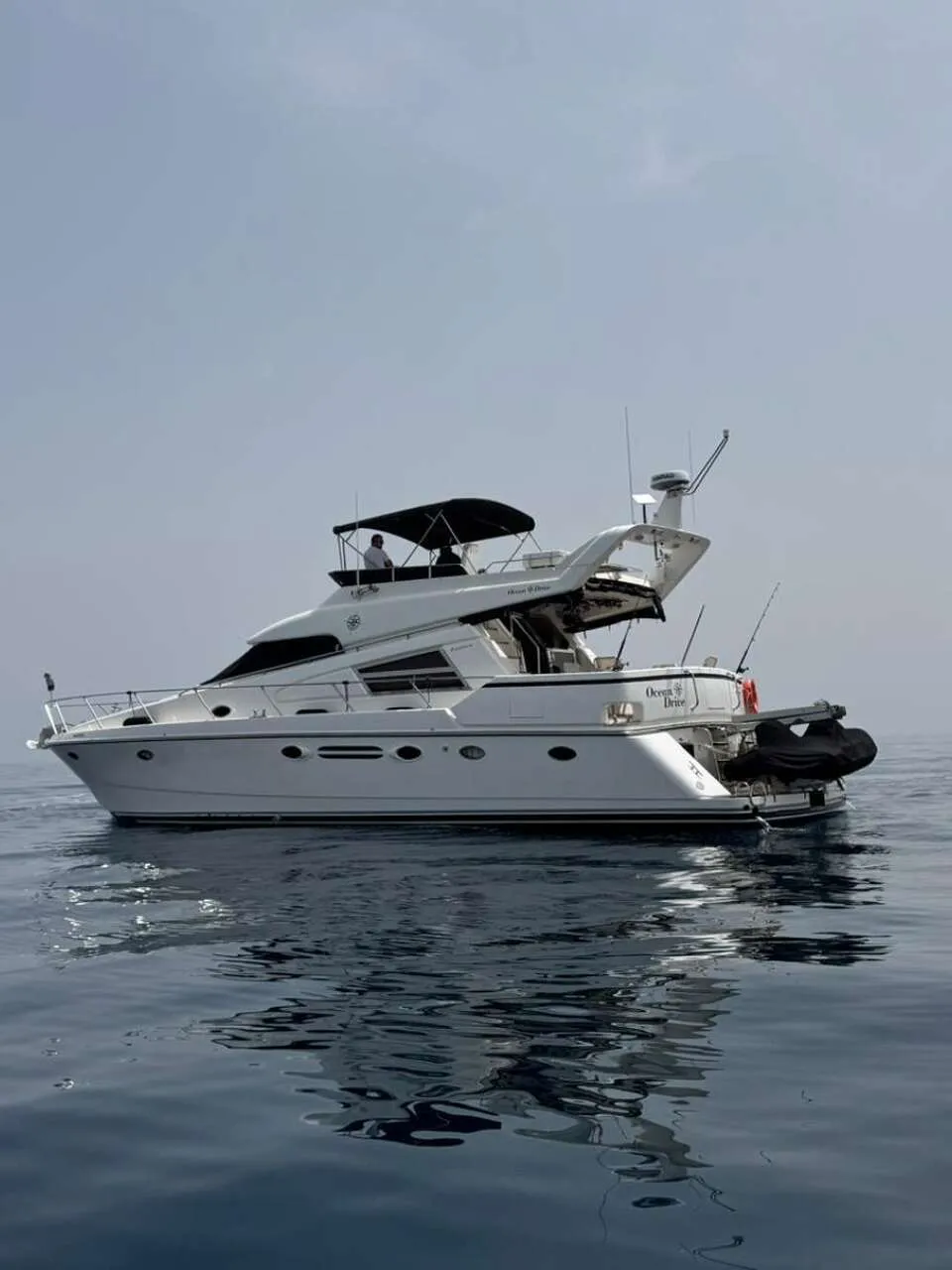 Een witte motorboot met de naam "Ocean Drive" vaart op kalm water onder een lichtgrijze lucht. — Johnson 56