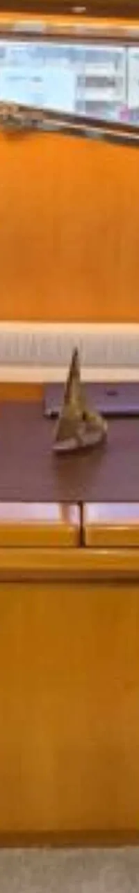 Een interieur van een boot met een U-vormige bank, een houten tafel en ramen met uitzicht op gebouwen. — Johnson 56