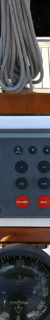 Een stuurstand met een Raymarine autopilot, een thruster bediening en een kompas, omringd door een teakhouten dek.