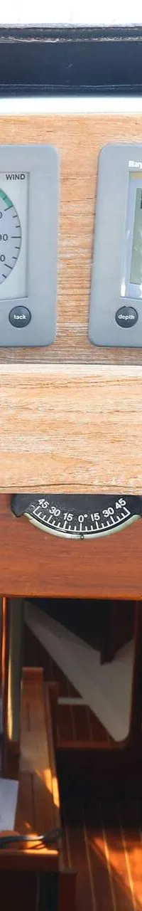 Vier Raytheon/Raymarine displays zijn gemonteerd boven een houten paneel, met daaronder een kompas en een kajuitinterieur.