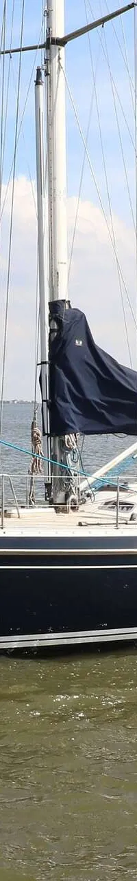Een donkerblauwe zeilboot met een witte streep vaart op het water, met een vlag aan de achtersteven. — Victoire 1270