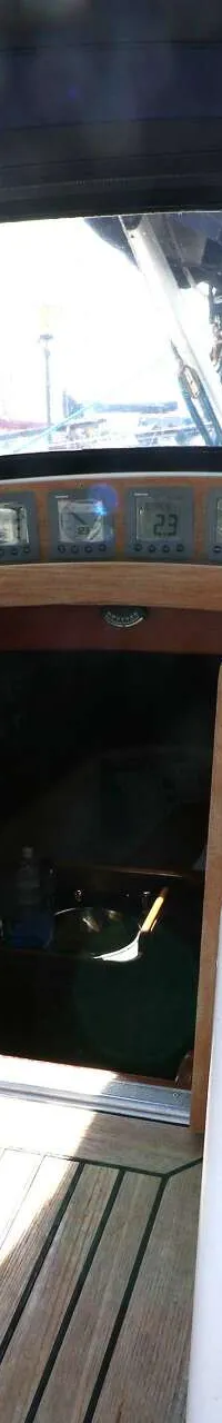 Een interieurfoto van een boot met een houten vloer, een open kajuitingang en diverse touwen en lieren. — Victoire 1270