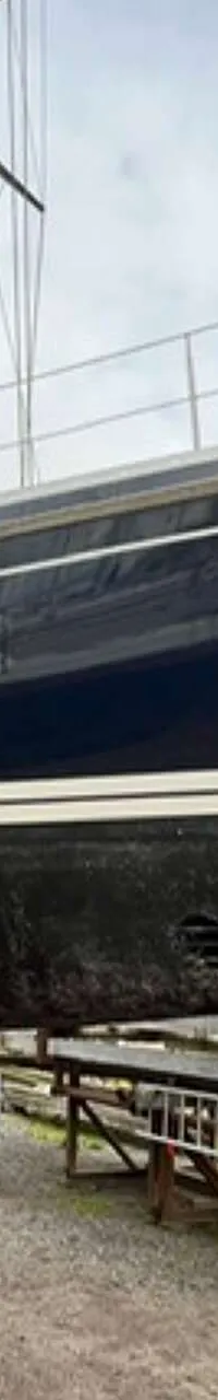 Een donkerblauwe zeilboot staat op bokken op de wal, met een logo van "DE VALK YACHT BROKERS" rechtsboven. — Victoire 1270