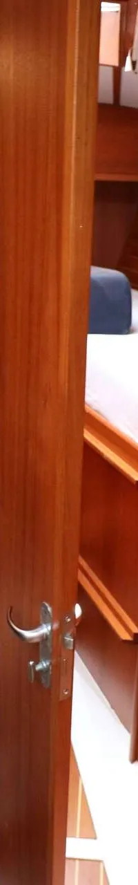 Een interieur van een boot met houten wanden en deuren, een toilet en een bed zijn zichtbaar. — Victoire 1270
