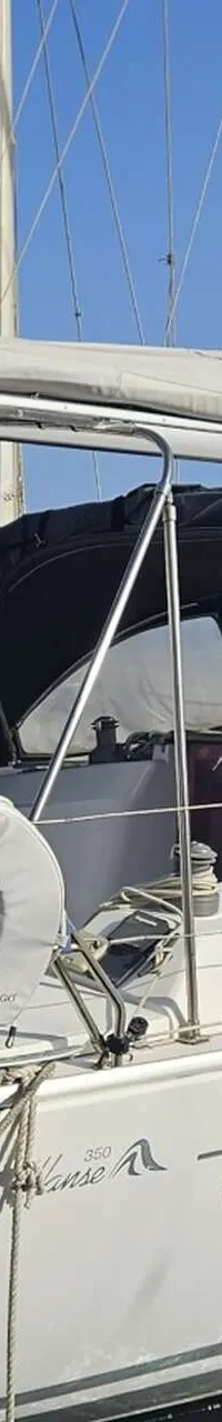 Een witte zeilboot met een zwarte buiskap en bimini ligt aangemeerd, met de registratie "93817-A" en "Hanse 350" op de romp.