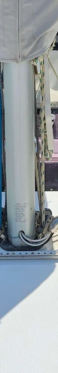 Een bovenaanzicht van het voordek van een witte zeilboot met een mast, lijnen, luiken en een buiskap. — Hanse 350