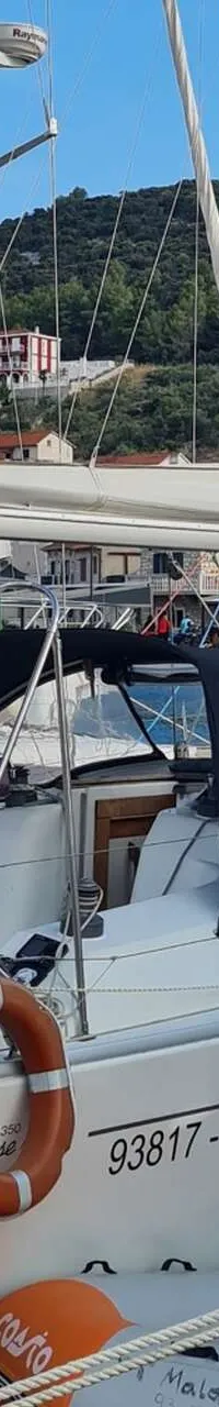 Een witte zeilboot met een zwarte buiskap en een reddingsboei ligt aangemeerd in een haven. — Hanse 350