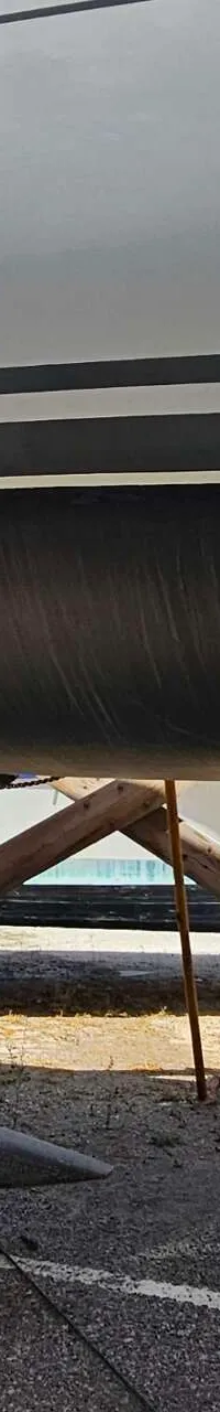 Een witte boot met een zwarte onderkant staat op de wal, ondersteund door stutten en kettingen. — Hanse 350