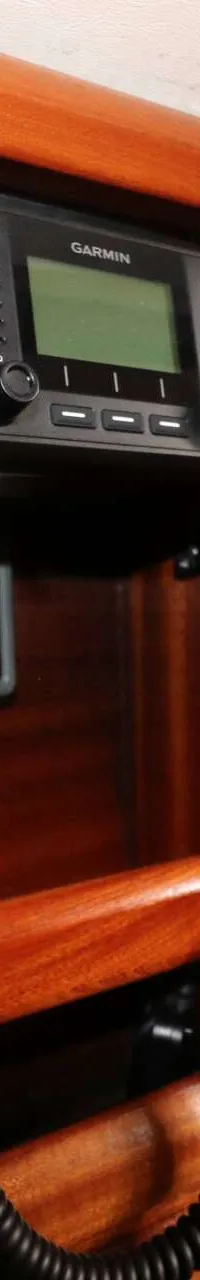Een Garmin marifoon en een ander display zijn gemonteerd op een glanzende, houten wand.