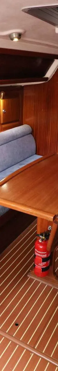 De foto toont het interieur van een boot met een kombuis, zithoeken, een tafel en een brandblusser. — Bavaria 31