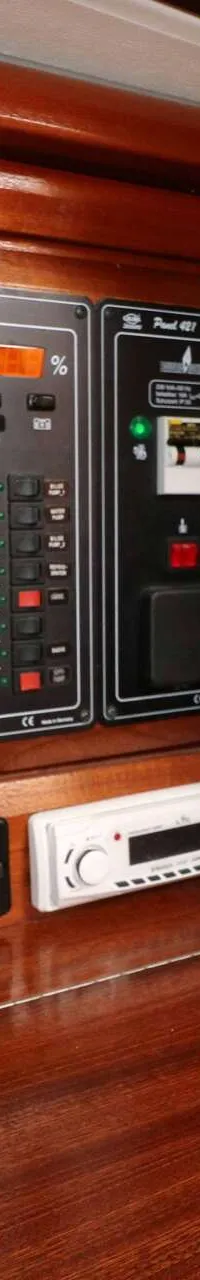 Een houten paneel met een elektrisch bedieningspaneel, een Webasto-regelaar en een autoradio.