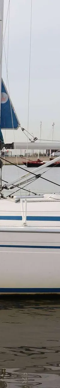 Een witte zeilboot met blauwe strepen en een blauwe buiskap ligt in het water. — Bavaria 31