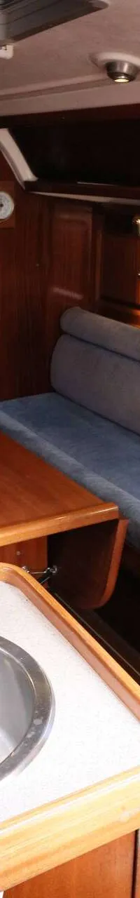 De foto toont het interieur van een boot met een kombuis, zithoek en houten afwerking. — Bavaria 31