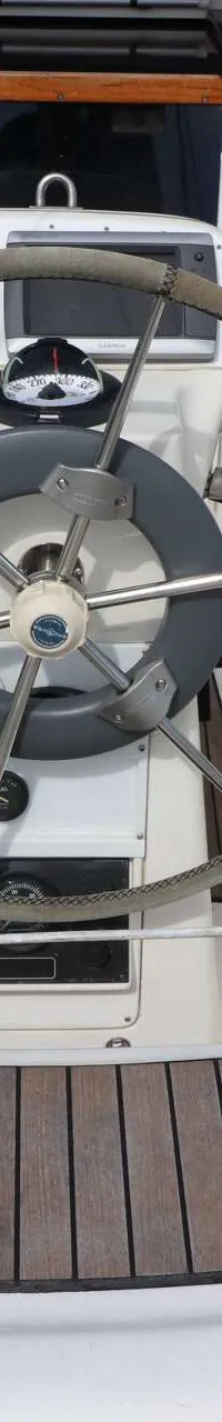 Een stuurwiel met kompas en navigatie-instrumenten in de kuip van een zeilboot met teakhouten dek. — Bavaria 31