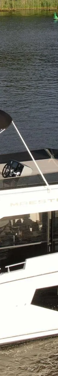 Een witte motorboot met twee dekken vaart op het water, met een zwarte bimini op het bovendek. — Cobra Yachts Maestro 42
